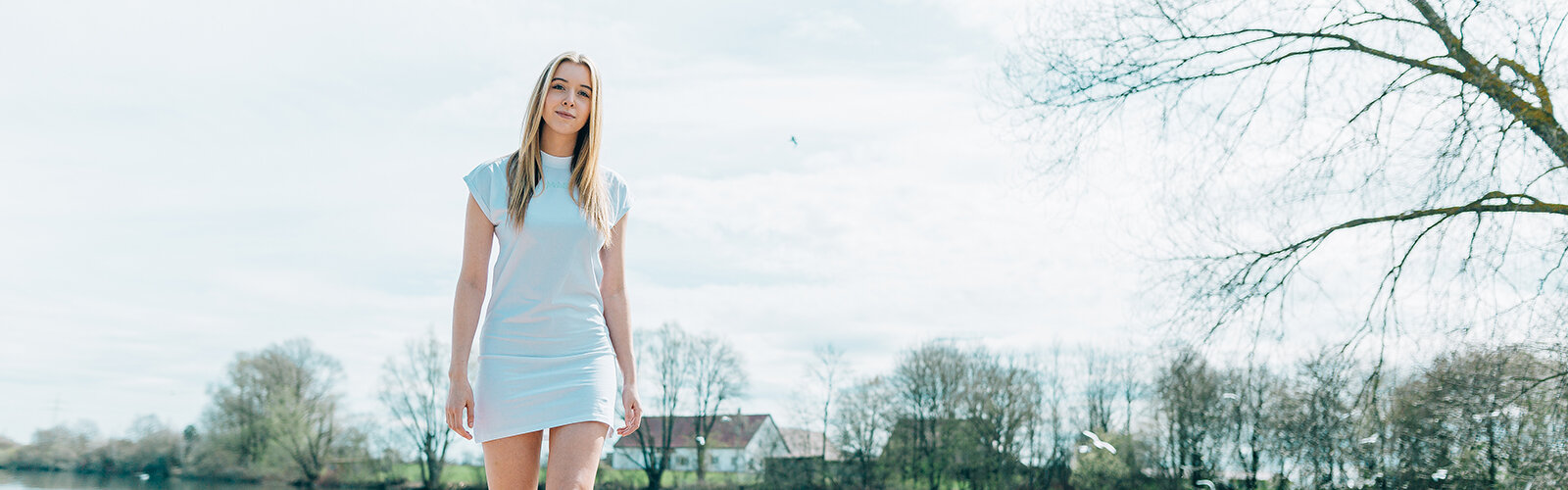 Mädchen in weißem T-Shirt Kleid an einem Steg